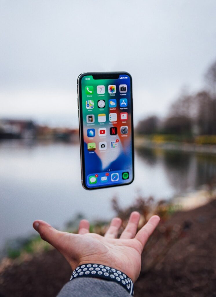 silver iPhone X floating over open palm